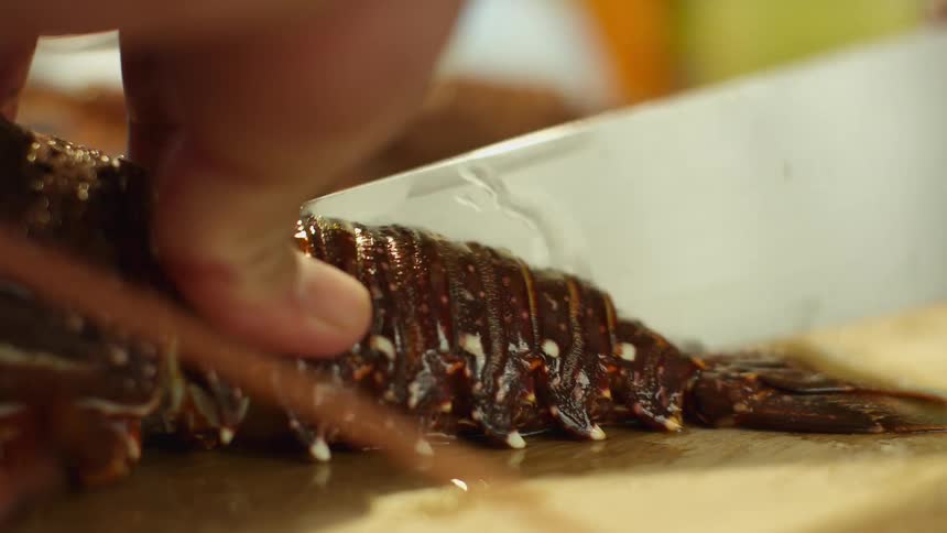 A person is cutting a lobster in the kitchen
