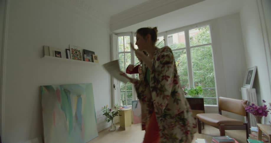 A woman moves around a man as she directs a man playing violin