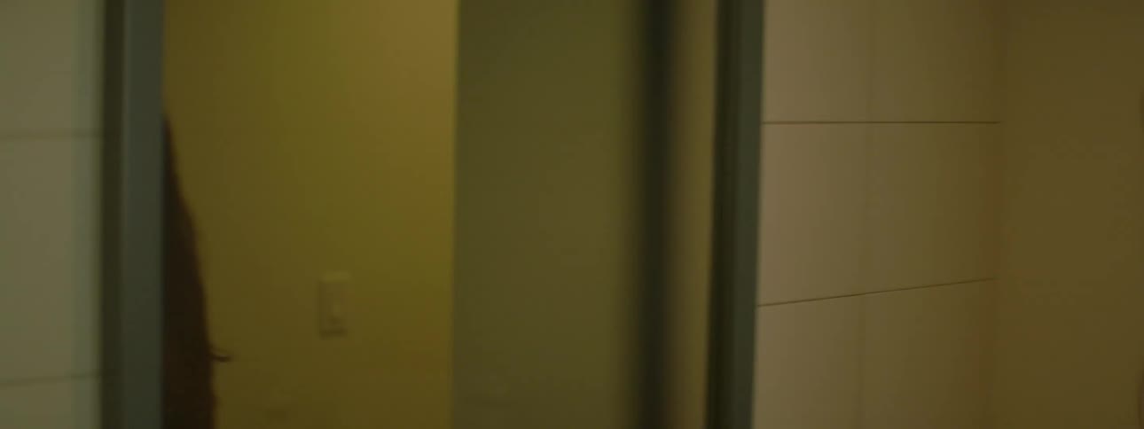 A woman stands in front of a mirror and turns around