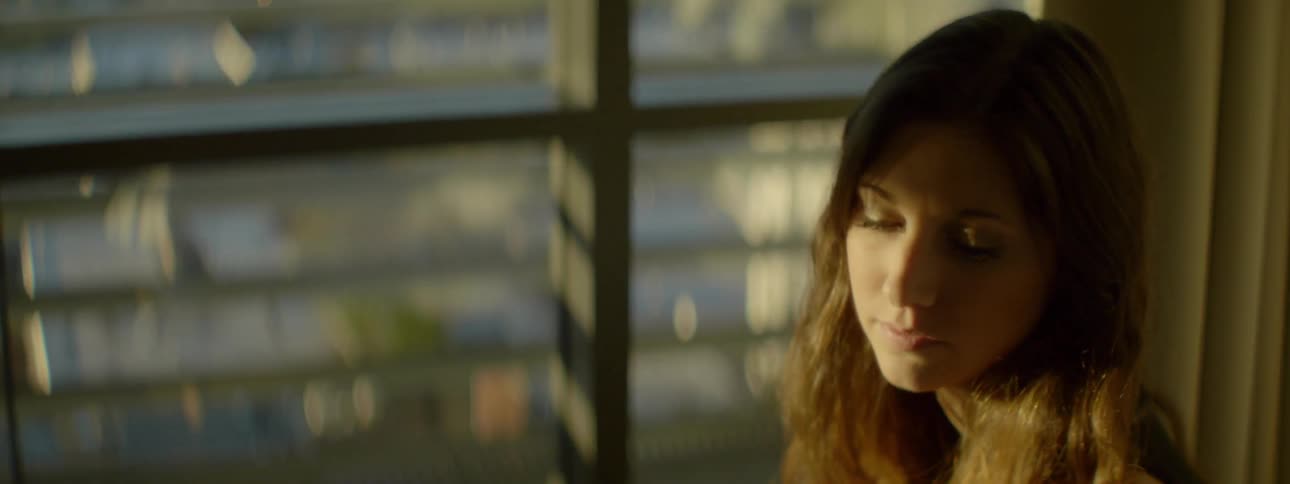 A woman is sitting near a window on a sunny day