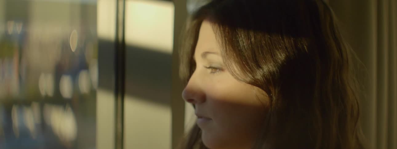 A brown haired woman looks out a window