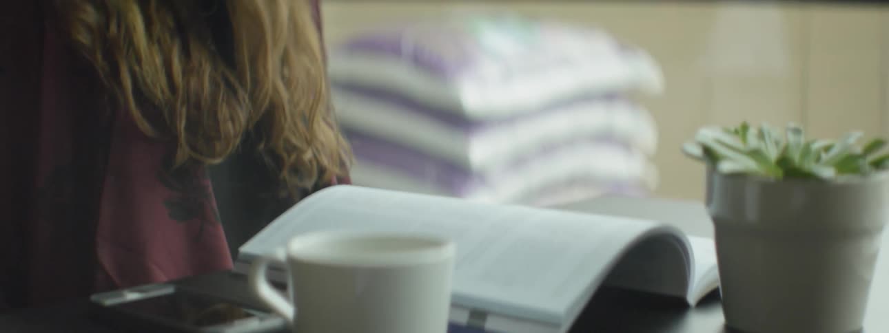 A woman in a hat reads a book on a table