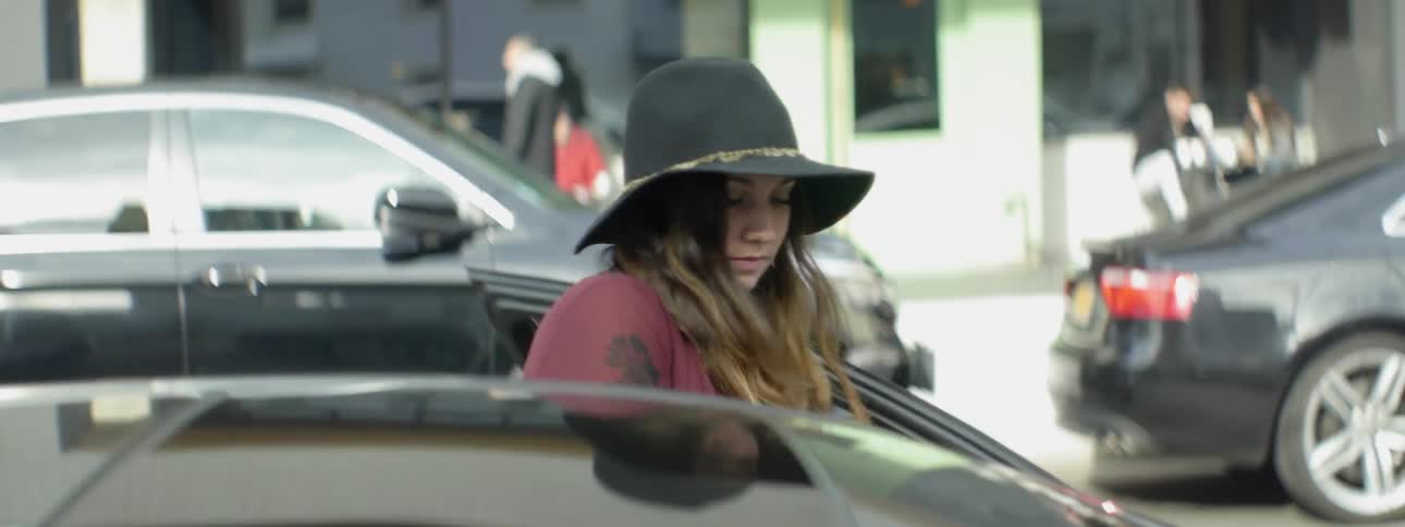 Woman in a hat gets into a car