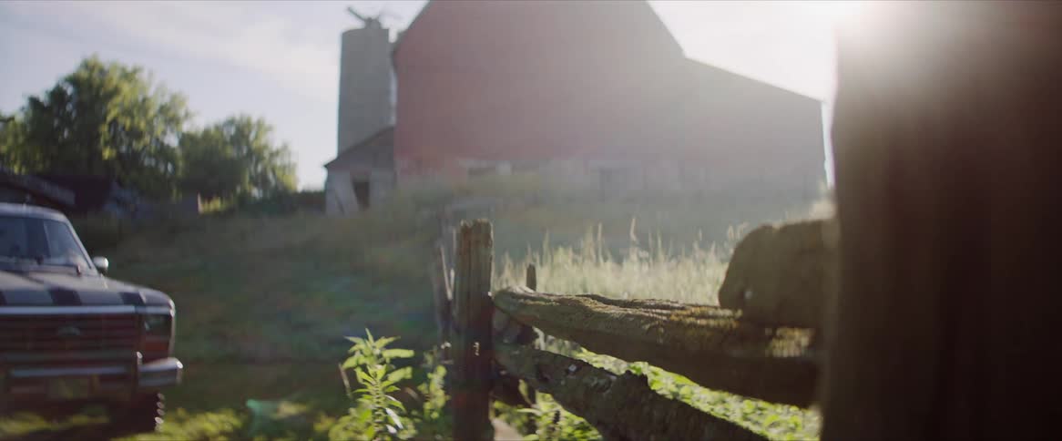A barn and an old truck on farmland in the country on a sunny day