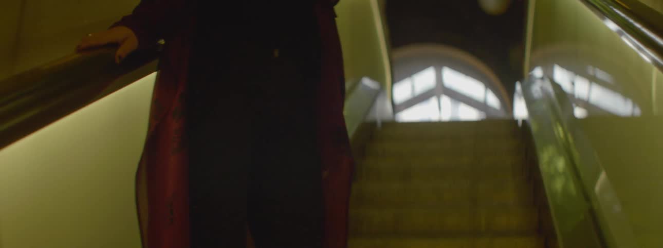 A woman is riding an escalator looking down