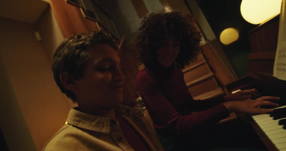 A woman is teaching a boy how to play a piano