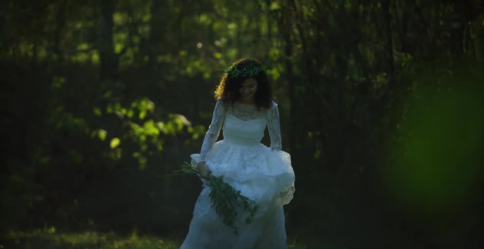 Young bride wearing a white wedding dress jumping on a garden at morning