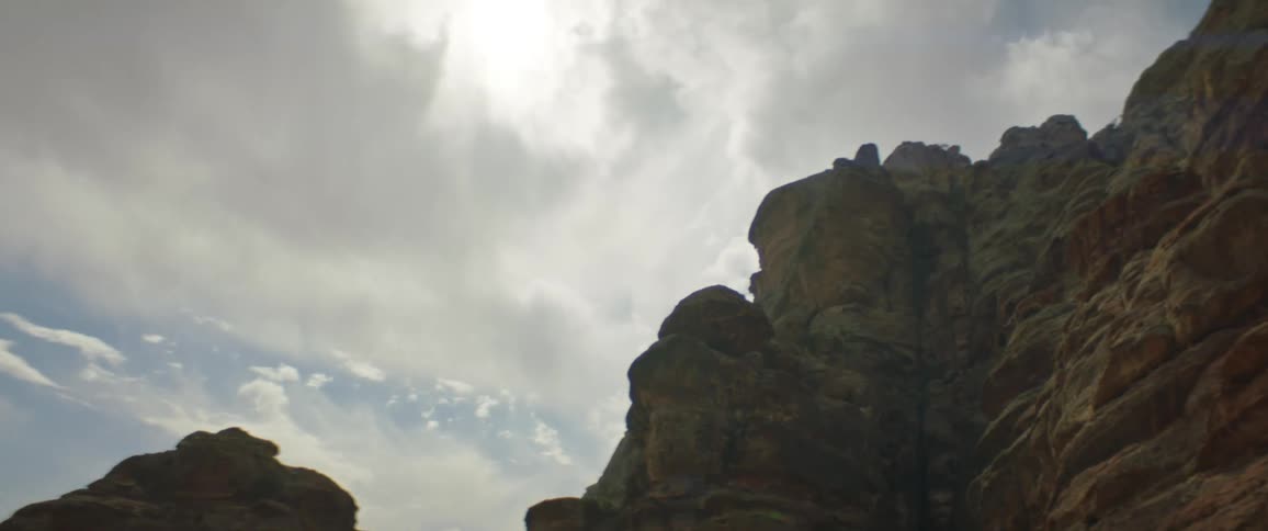Rough rocky cliff stands under cloudy sky