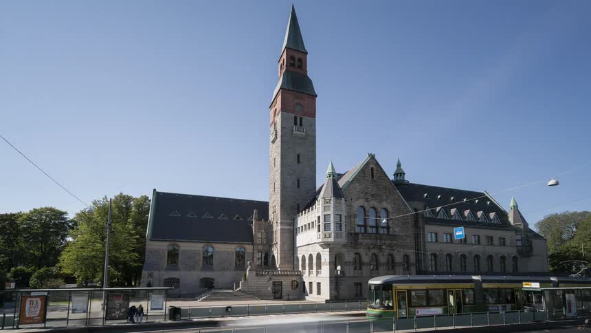 A train passes by a church with a steeple high in a blue sky