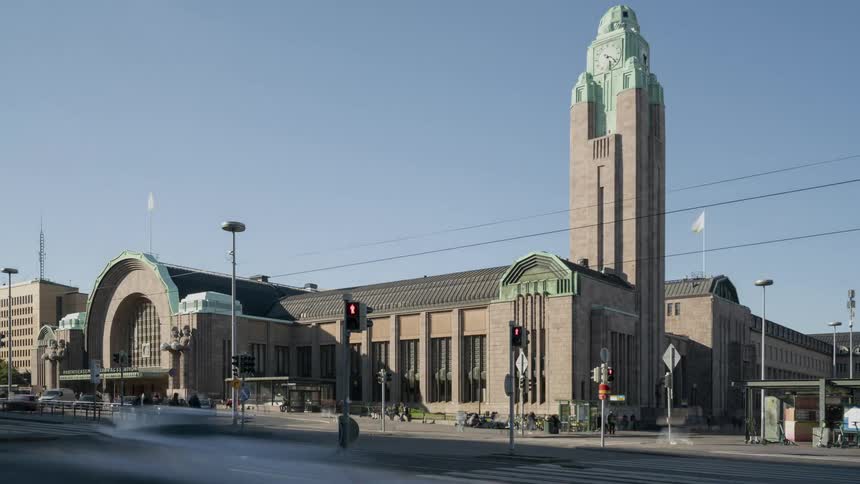 A city street with vehicles and pedestrians with buildings the sky and clouds in the background