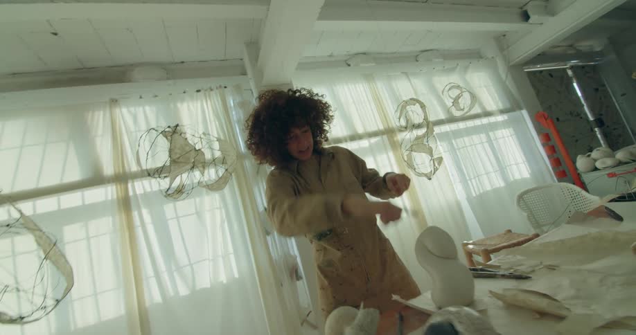 A boy and a woman in a room with a wall windows and curtains in the background