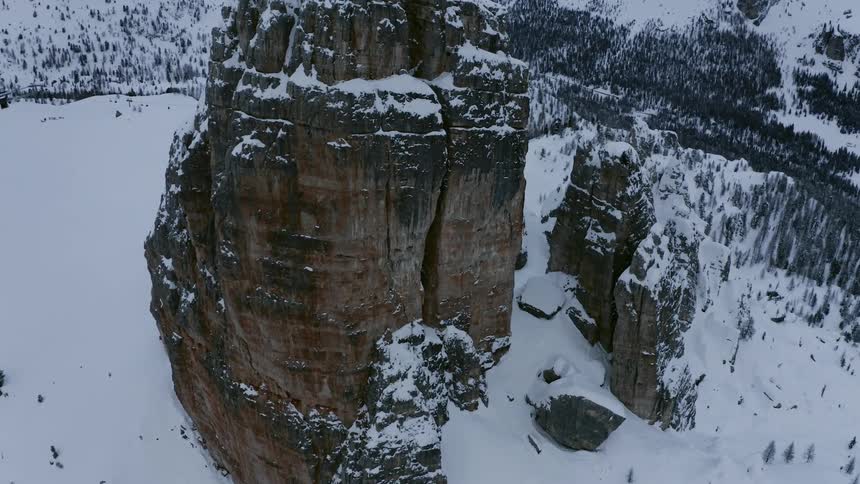 A tall mesa sticks out from a snow covered mountain range