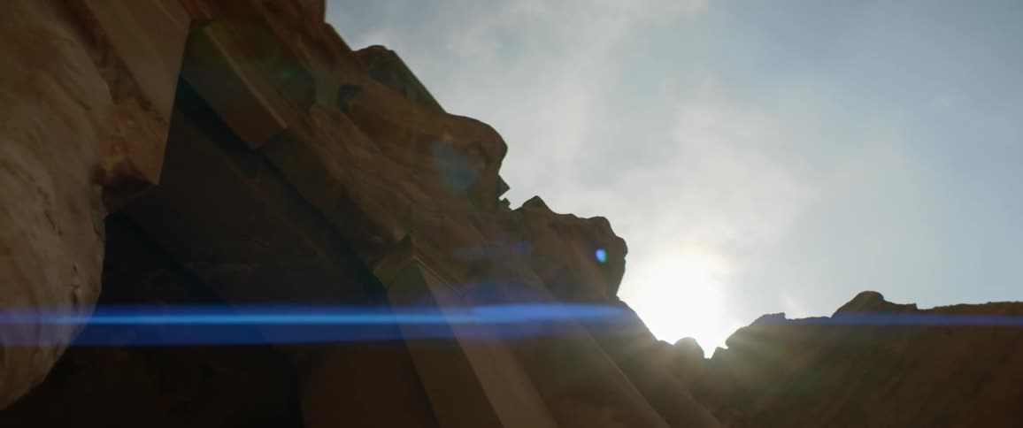 Sun shining over the entrance of a building carved on the side of a mountain