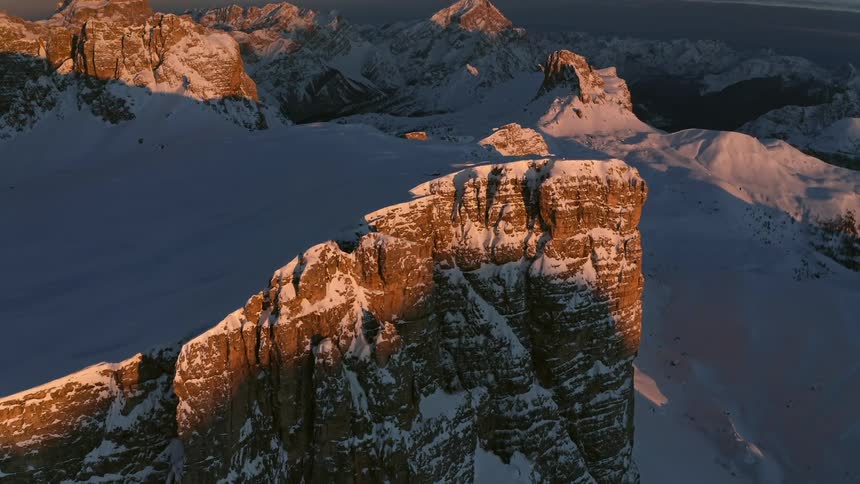 A mountain range covered in snow and ice with the sky and clouds in the background