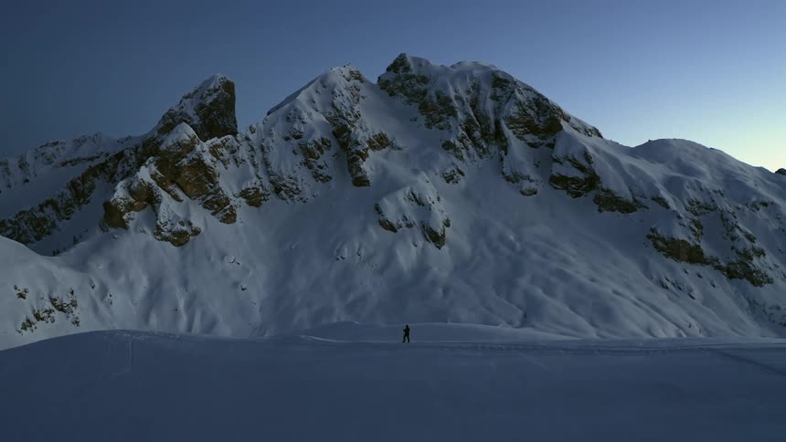 A person is hiking in the snow on the mountain range