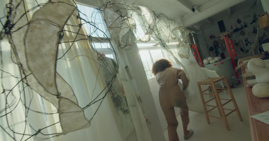 Two women are chasing each other through some curtains in an art room
