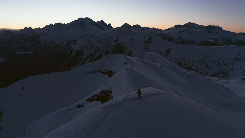 A person walks up a snowy mountain