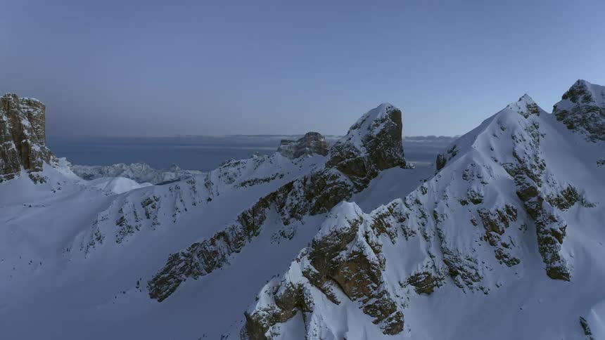 A thick blanket of snow covers the top of a mountain