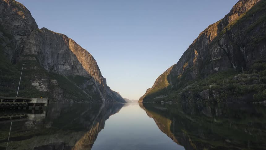 Time lapse of the calm waters on a river between the mountains at morning
