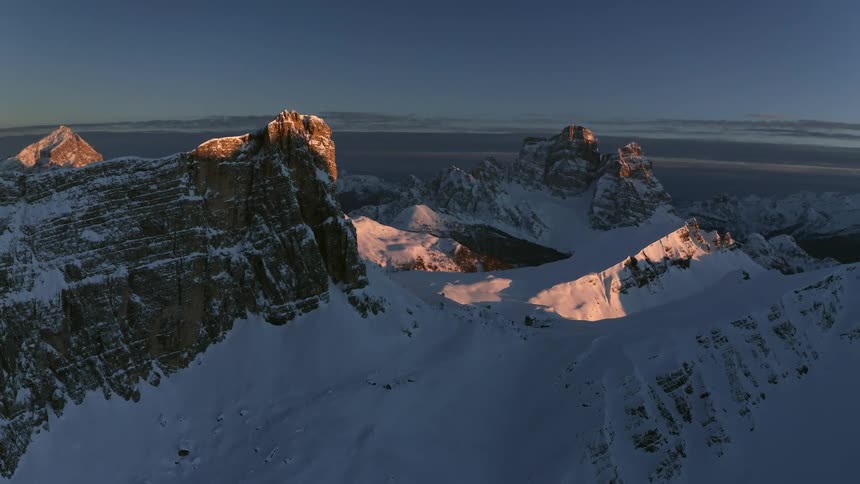 A mountain range covered in snow and ice with the sky and clouds in the background