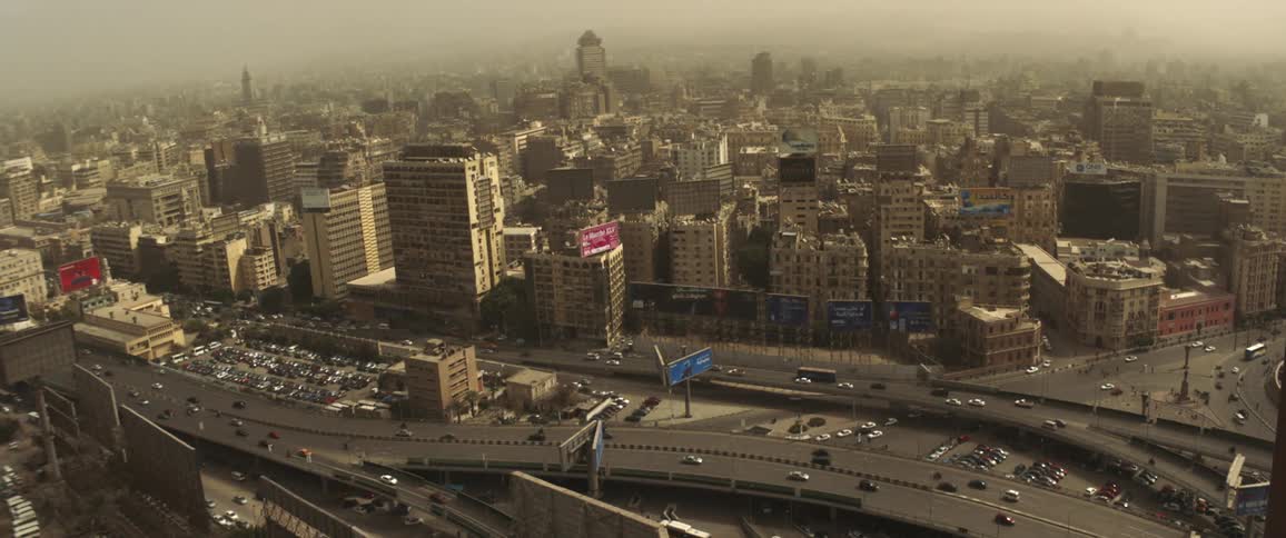 Traffic flows across highway through city partly covered in fog