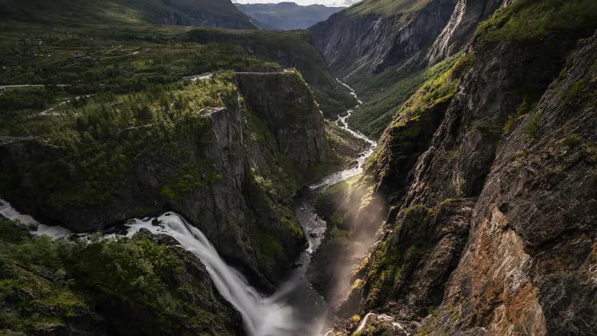 Waterfalls flow down the side of a mountain as clouds move overhead
