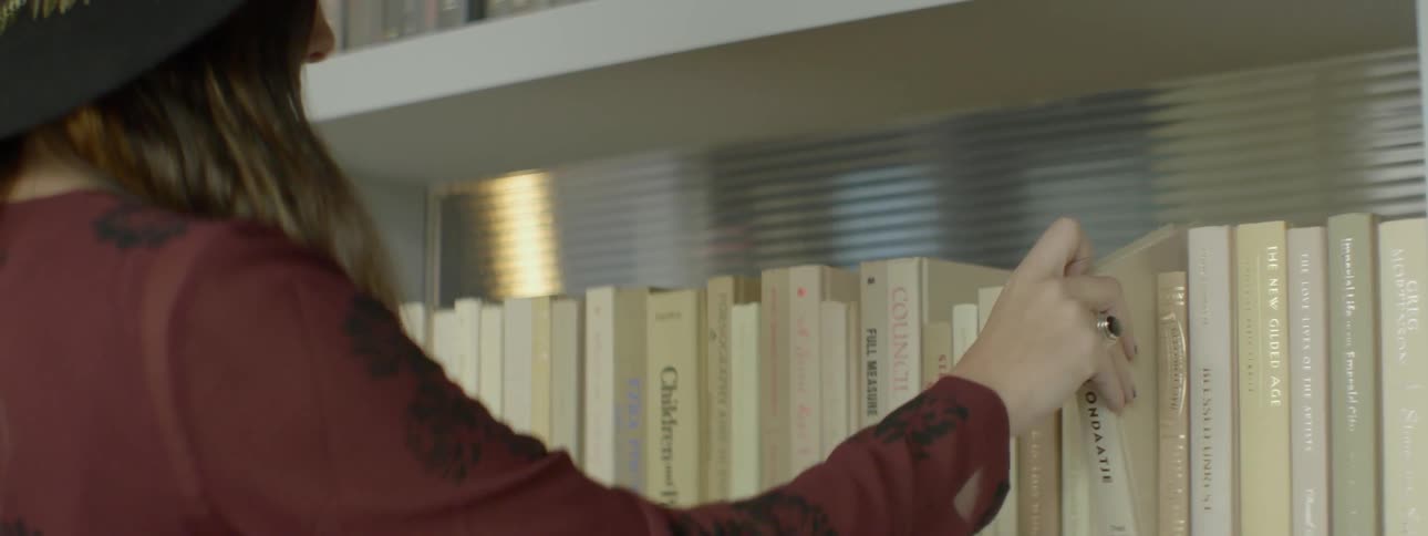 A woman examines some books on the shelf