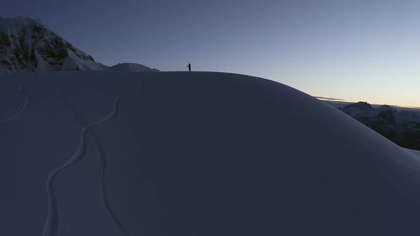 A person is standing on the top of a snow covered mountain