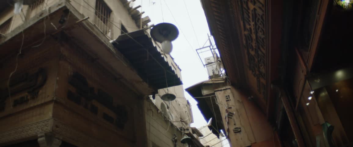 Light flickers near storefront as wires occupy area above alley