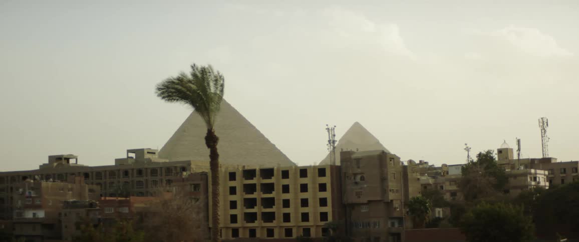 The egyptian pyramids behind other buildings in egypt on cloudy day