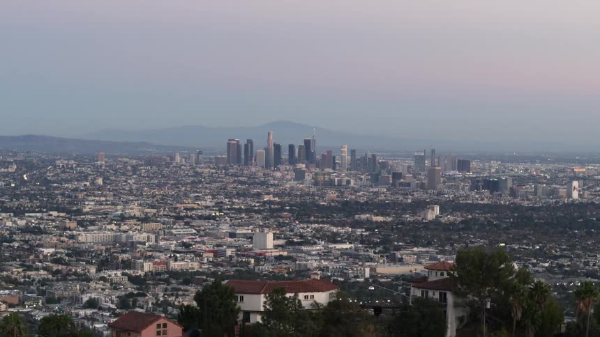 Houses on a hilltop overlooking towers and buildings in the city skyline
