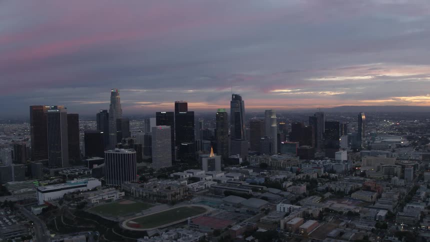 A blue hour aerial shot of Downtown Los Angeles with a lit Christmas tree atop a building