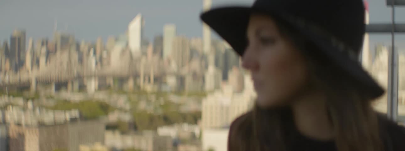 Woman wearing a hat looking out over a large city