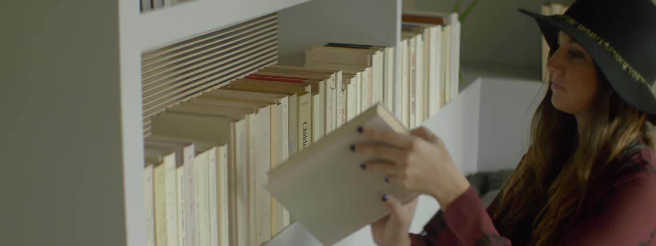 Woman placing a book back with others on a bookshelf
