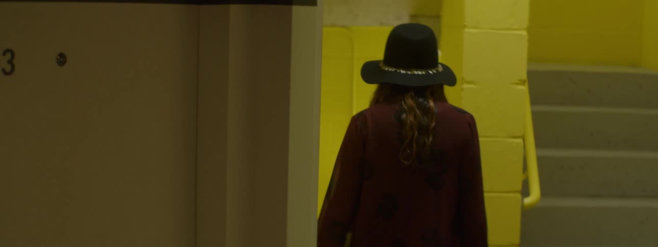 A woman walks out of a dark lot into a staircase