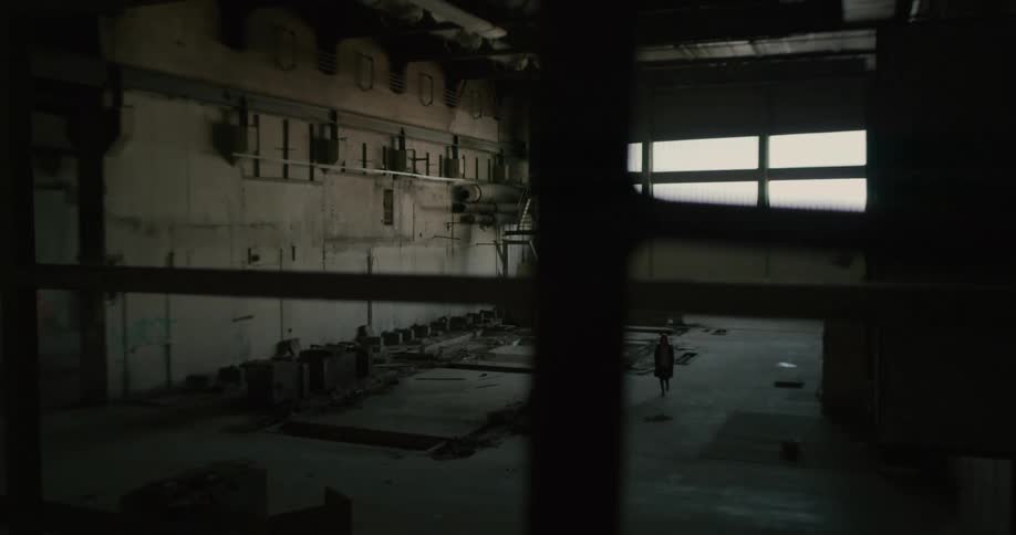 The silhouette of a woman walking in an abandoned factory warehouse