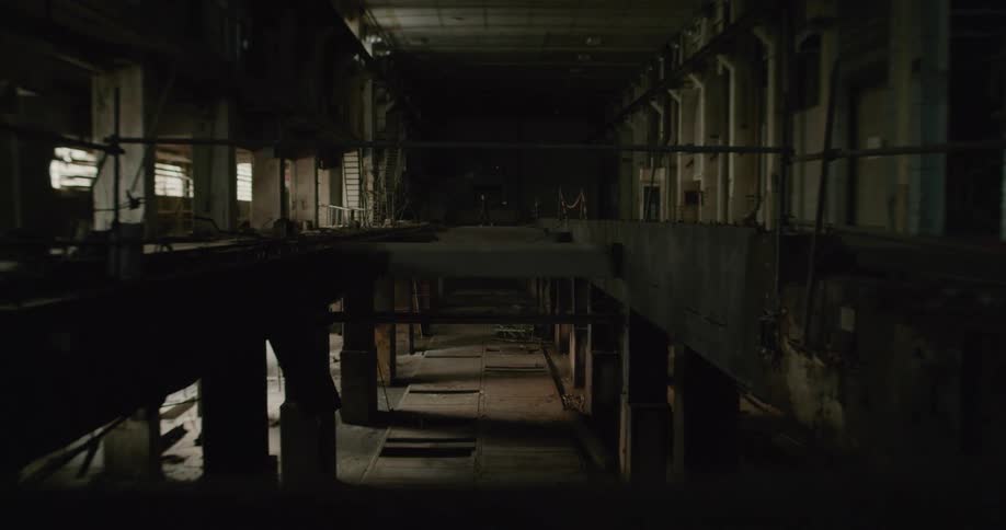 A person walking in an abandoned factory with pillars