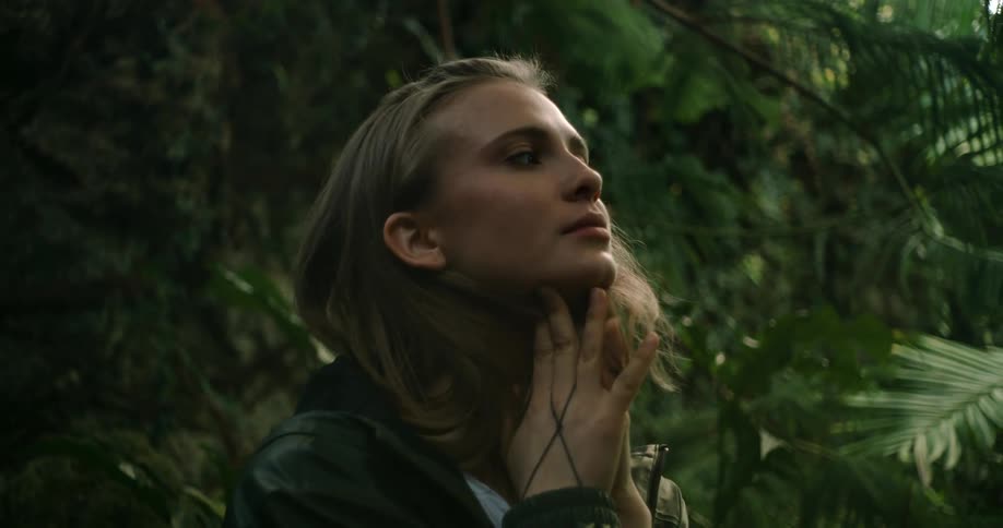 A woman standing outdoors in a forest area