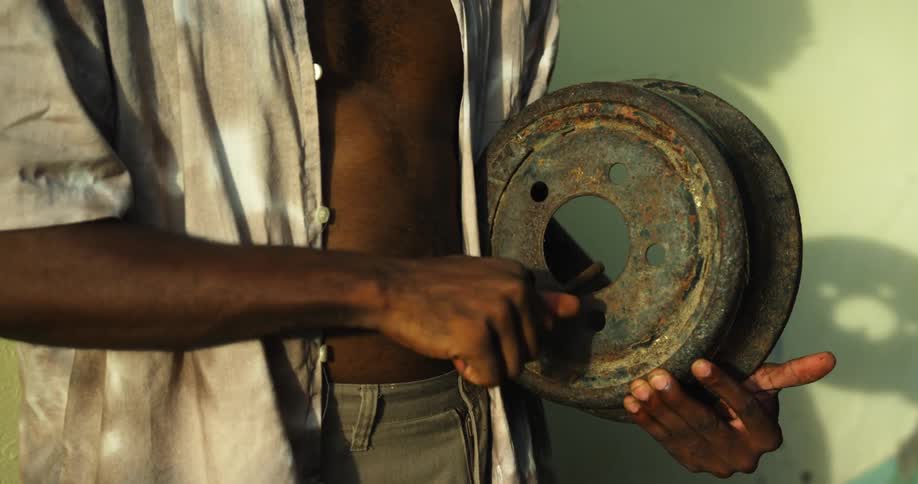 A man playing sounds on a old piece of metal