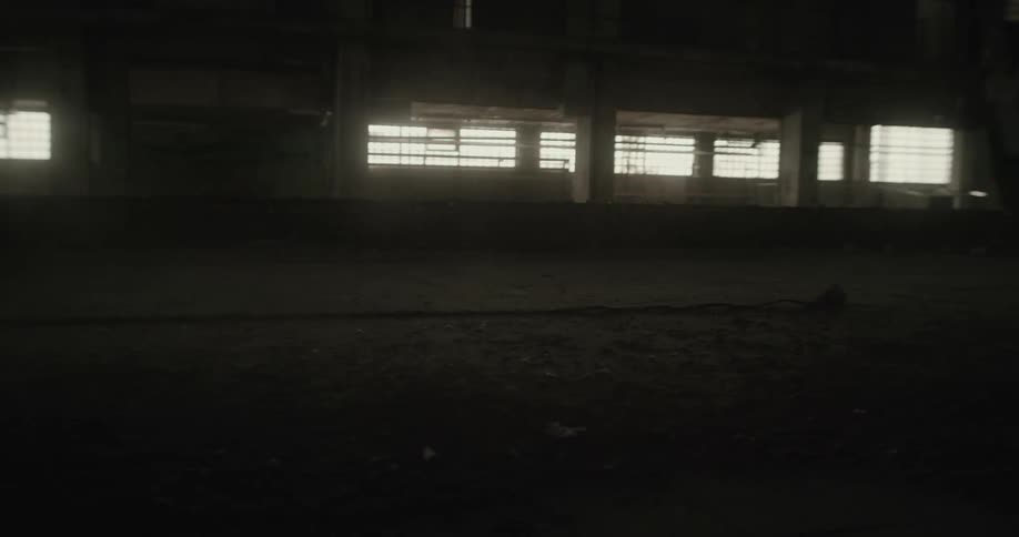 Blonde woman runs through dimly lit abandoned building