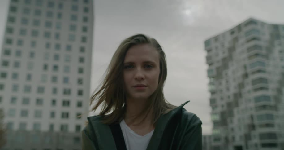 Portrait of a young woman standing in an urban area of a city staring into the camera on a dreary fall season day