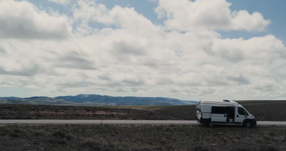 A van is parked on the side of a rural country road on a cloudy day