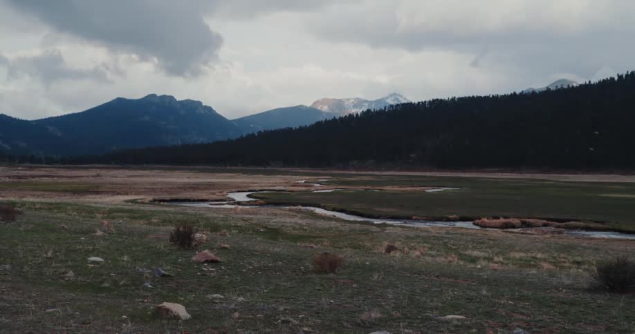 A landscape with a stream with a mountain range the sky and clouds in the background