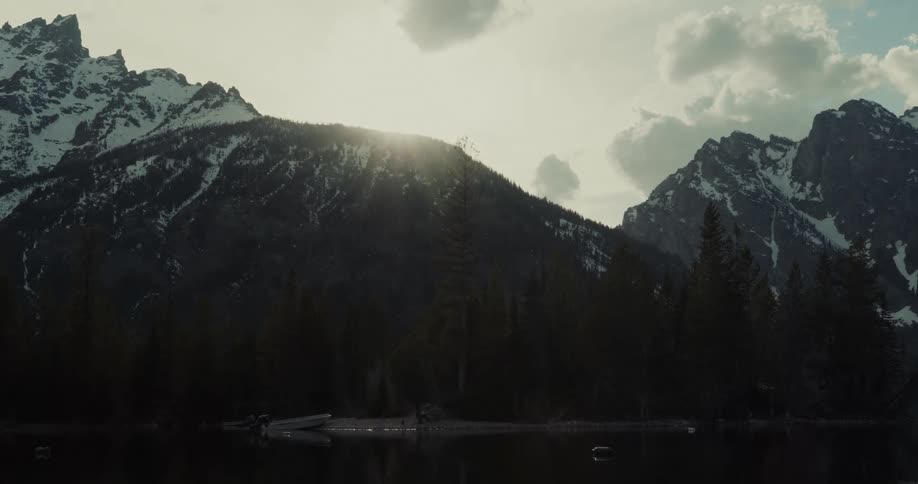 A small boat is on the shore by the mountain