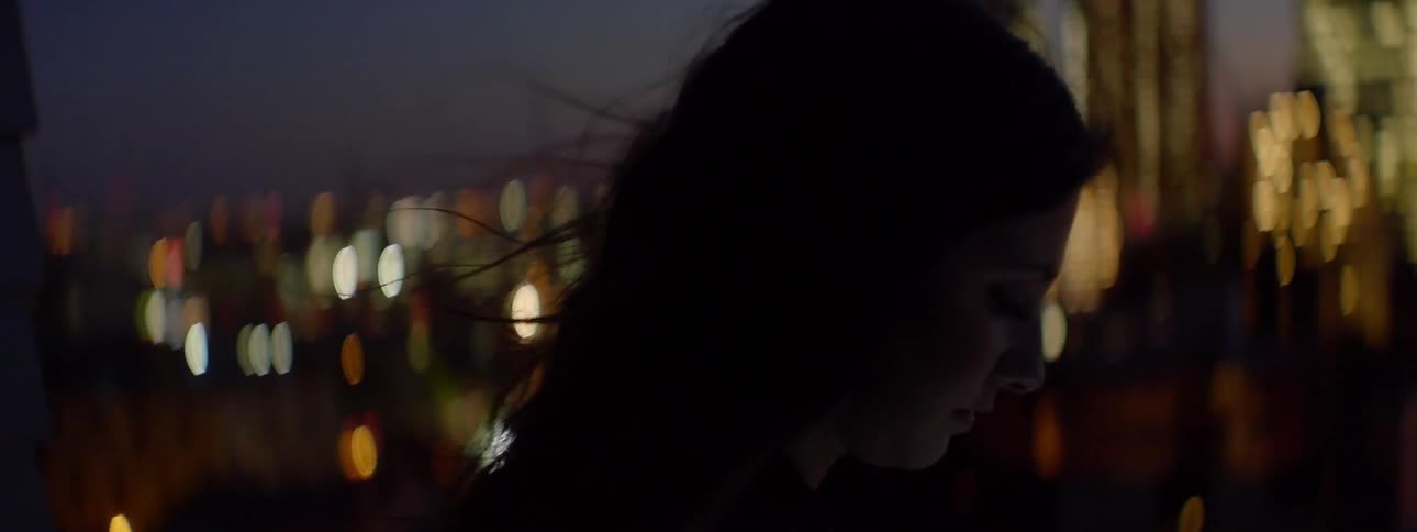 A woman looks over a city at night