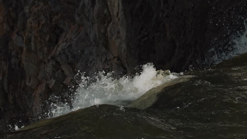 Rapidly flowing water of a river is splashing and foaming as it goes over and edge in the daytime