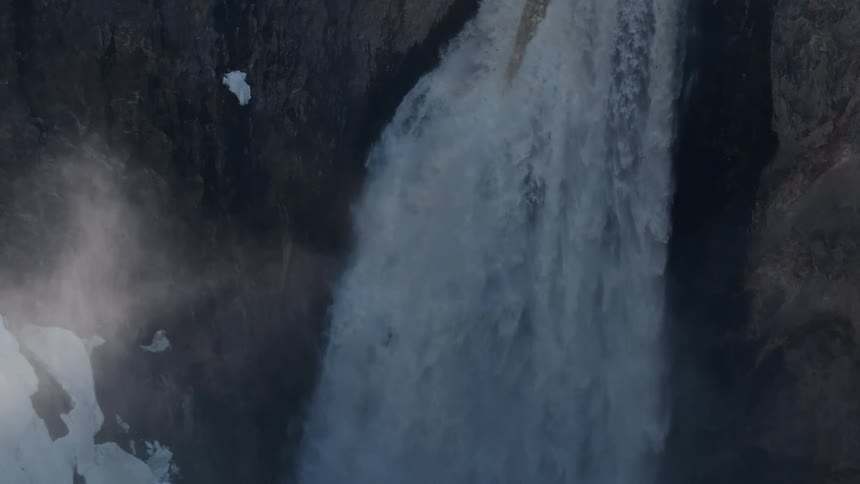 A river flows off a sheer cliff creating a white water waterfall