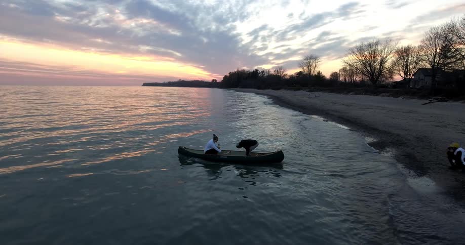 People push off in a canoe into the ocean at dusk