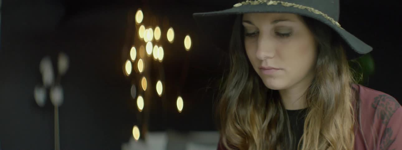 A woman in a black hat looks up from her phone