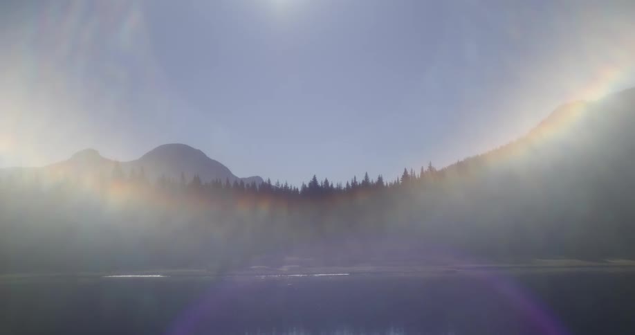 A forest and a mountain range sit near the water
